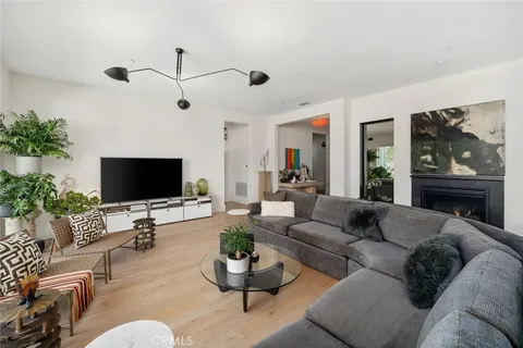 a living room with furniture potted plant floor to ceiling window and a flat screen tv