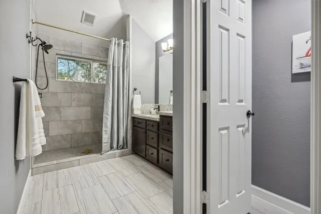 a bathroom with a granite countertop shower a mirror and a sink