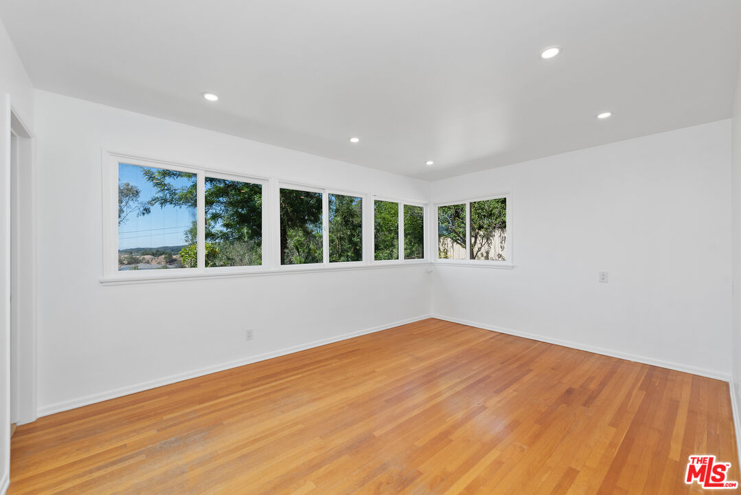1211 North Kenter Avenue Los Angeles, CA 90049 - Photo 5 of 11 a view of an empty room with wooden floor and a window
