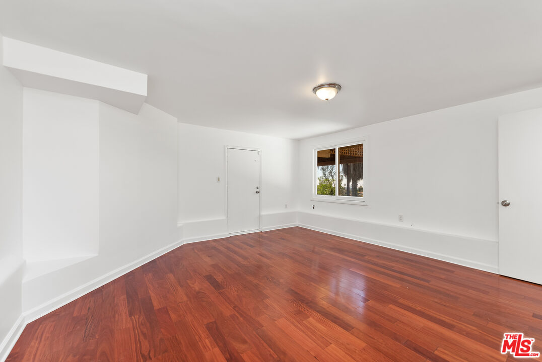 1211 North Kenter Avenue Los Angeles, CA 90049 - Photo 8 of 11 a view of an empty room with wooden floor and a window