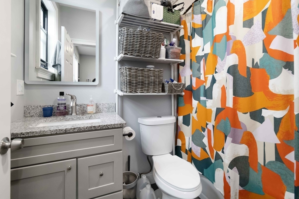 18 Albion Street, Unit 2 Boston, MA 02119 - Photo 7 of 22 a bathroom with a granite countertop toilet sink and a mirror