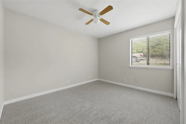 an empty room with a window and a fan