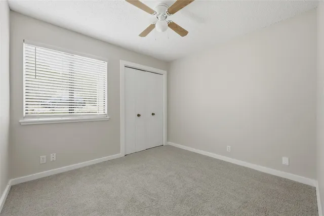 an empty room with a window and a ceiling fan