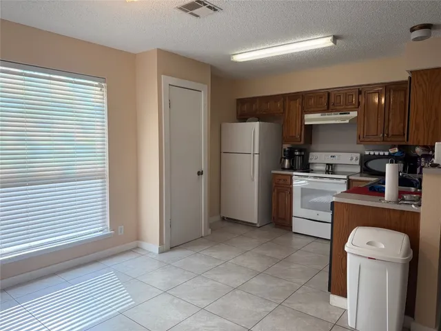 a kitchen with a refrigerator a stove top oven and cabinets