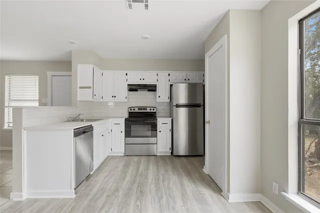 a kitchen with cabinets stainless steel appliances and window