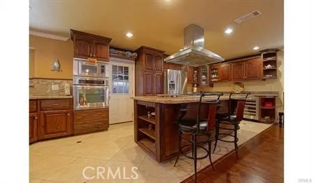 a kitchen with stainless steel appliances kitchen island granite countertop a stove a refrigerator and a wooden cabinets