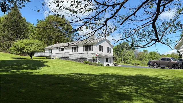 a white house with a big yard and large trees