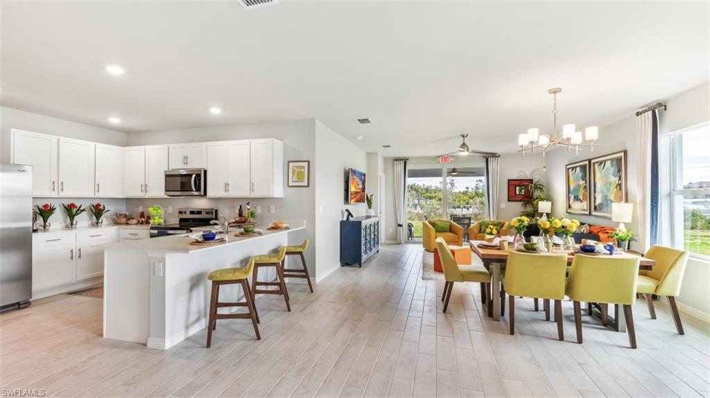 17613 Shade Tree Loop Punta Gorda, FL 33982 - Photo 6 of 27 a view of a dining room and livingroom with furniture wooden floor a rug a fireplace and a chandelier