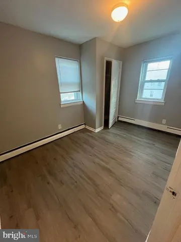 an empty room with wooden floor closet and windows