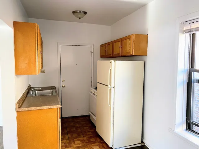 a bathroom with a sink a refrigerator and a window