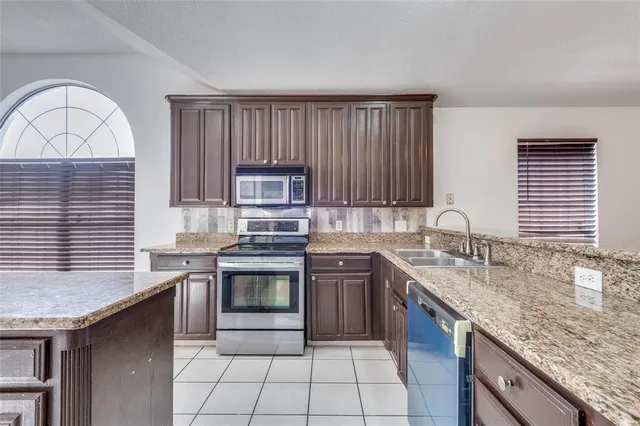 a kitchen with stainless steel appliances granite countertop a stove a sink and a microwave