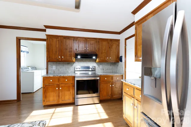 a kitchen with stainless steel appliances granite countertop a stove a sink and a refrigerator