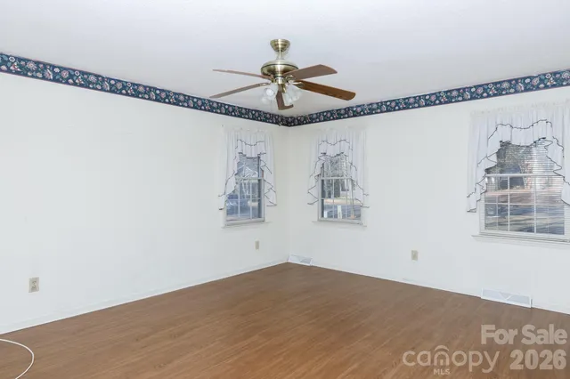 a view of a room with wooden floor chandelier and windows