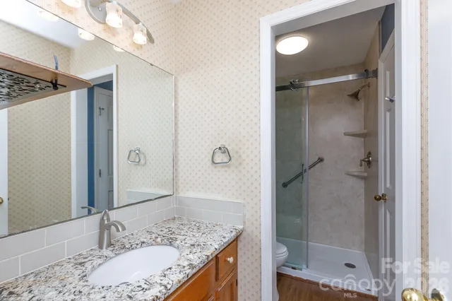 a bathroom with a granite countertop sink shower and a mirror