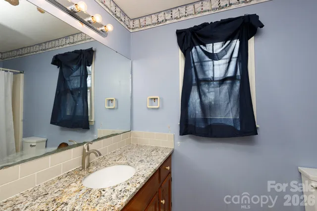 a bathroom with a granite countertop sink a mirror and shower