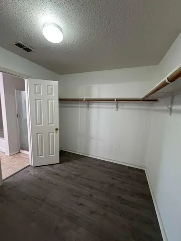 an empty room with wooden floor closet and windows
