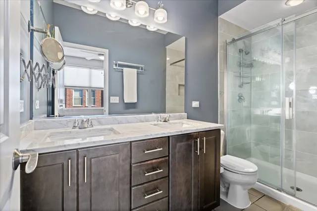a bathroom with a granite countertop sink a toilet a mirror and shower