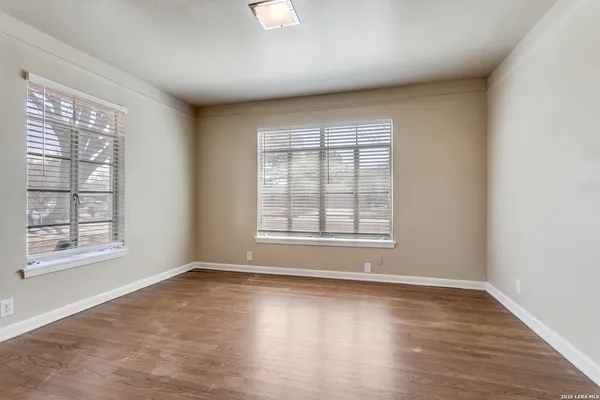 an empty room with wooden floor and windows