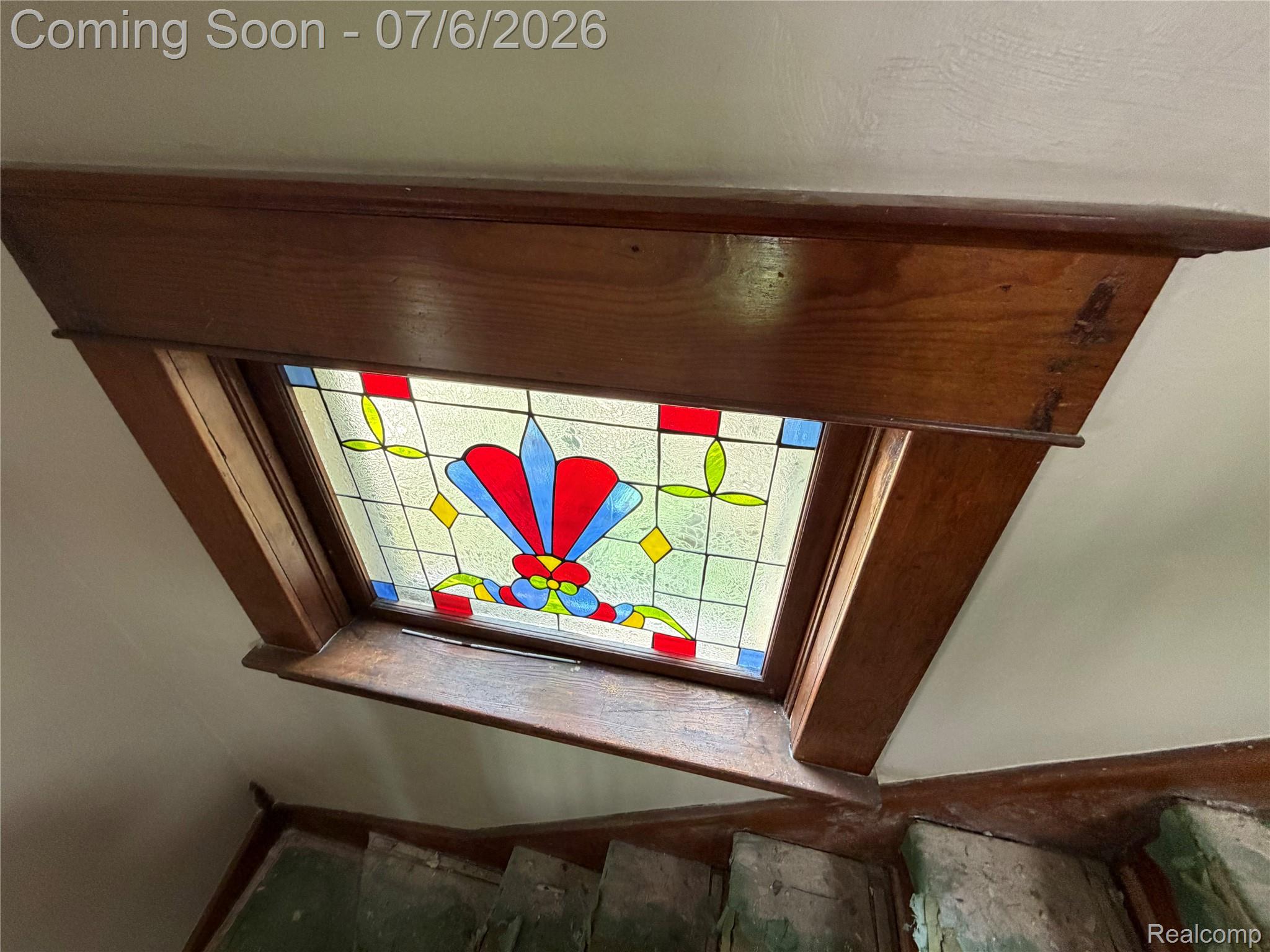 808 Division Street Owosso, MI 48867 - Photo 20 of 25 Stained glass window framed with rich wood trim, featuring vibrant red, blue, and yellow patterns