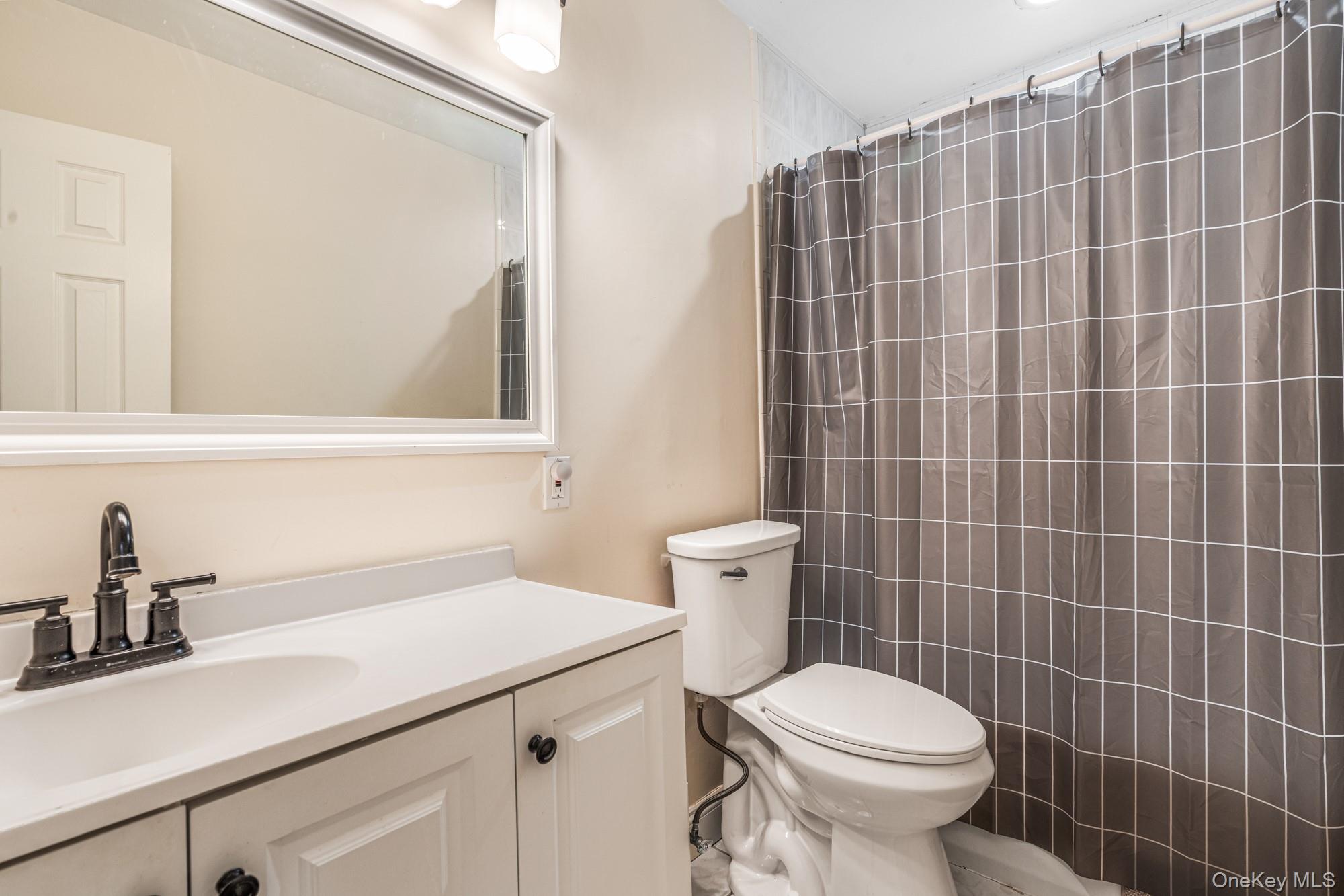 65 39th Street Islip, NY 11751 - Photo 11 of 30 a bathroom with a sink a toilet and a mirror