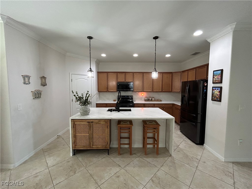 8963 Water Tupelo Road Fort Myers, FL 33912 - Photo 20 of 37 a kitchen with kitchen island a counter top space a sink stainless steel appliances and cabinets