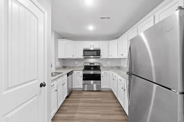 a kitchen with granite countertop a refrigerator stove and sink