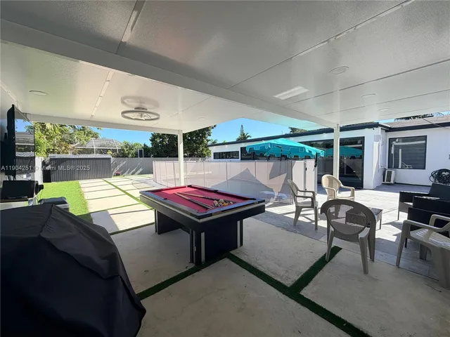 a view of a patio with a dining table and chairs with a barbeque grill