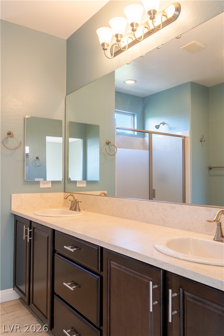 11045 Elk Sands Road Las Vegas, NV 89179 - Photo 26 of 67 An elegant double vanity offers ample storage space alongside contemporary lighting.