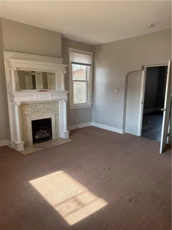 a view of an empty room with window and fire place