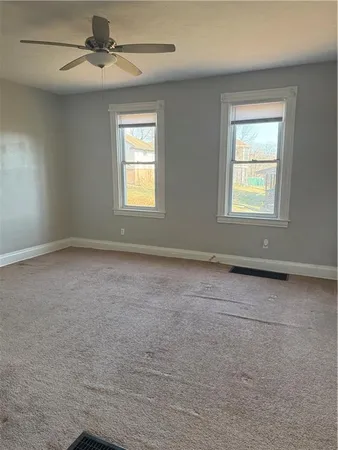 en empty room with windows and ceiling fan
