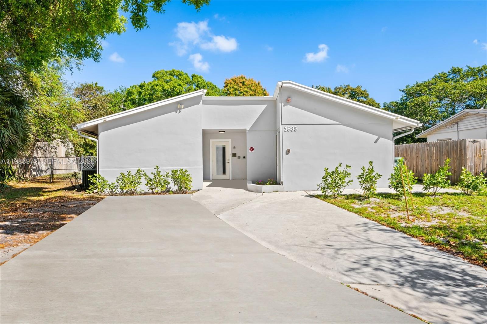 1633 Northwest 4th Street Boca Raton, FL 33486 - Photo 3 of 29 a view of a white house with a yard and potted plants