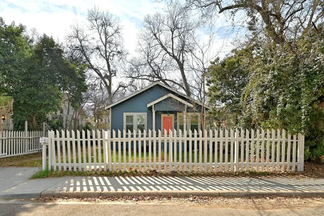 a view of a house with a small yard and wooden fence