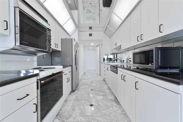 a large white kitchen with a sink and large mirror