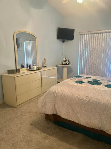 a bedroom with a bed and a flat tv screen on dresser