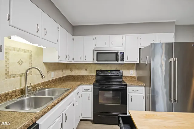 a kitchen with granite countertop white cabinets and stainless steel appliances