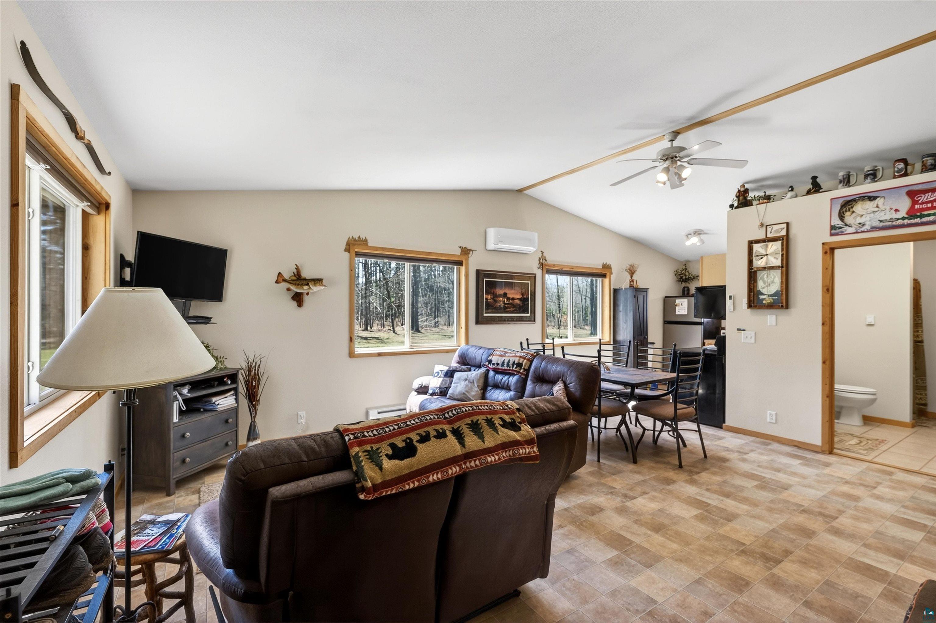 12235 East Crooked Lake Road Gordon, WI 54838 - Photo 22 of 48 Open-concept living area featuring vaulted ceilings, wood-finish flooring, and multiple windows with wood trim