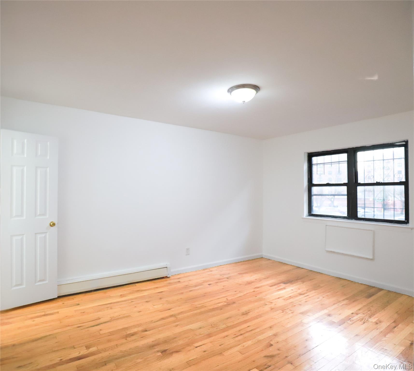 57-32 Xenia Street Queens, NY 11368 - Photo 11 of 12 an empty room with wooden floor and windows