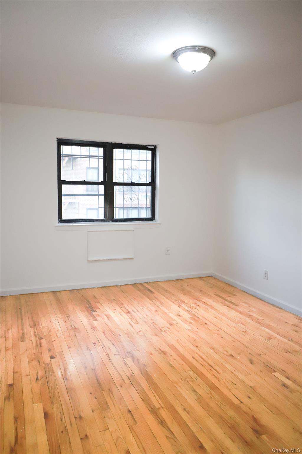 57-32 Xenia Street Queens, NY 11368 - Photo 2 of 12 an empty room with wooden floor and windows