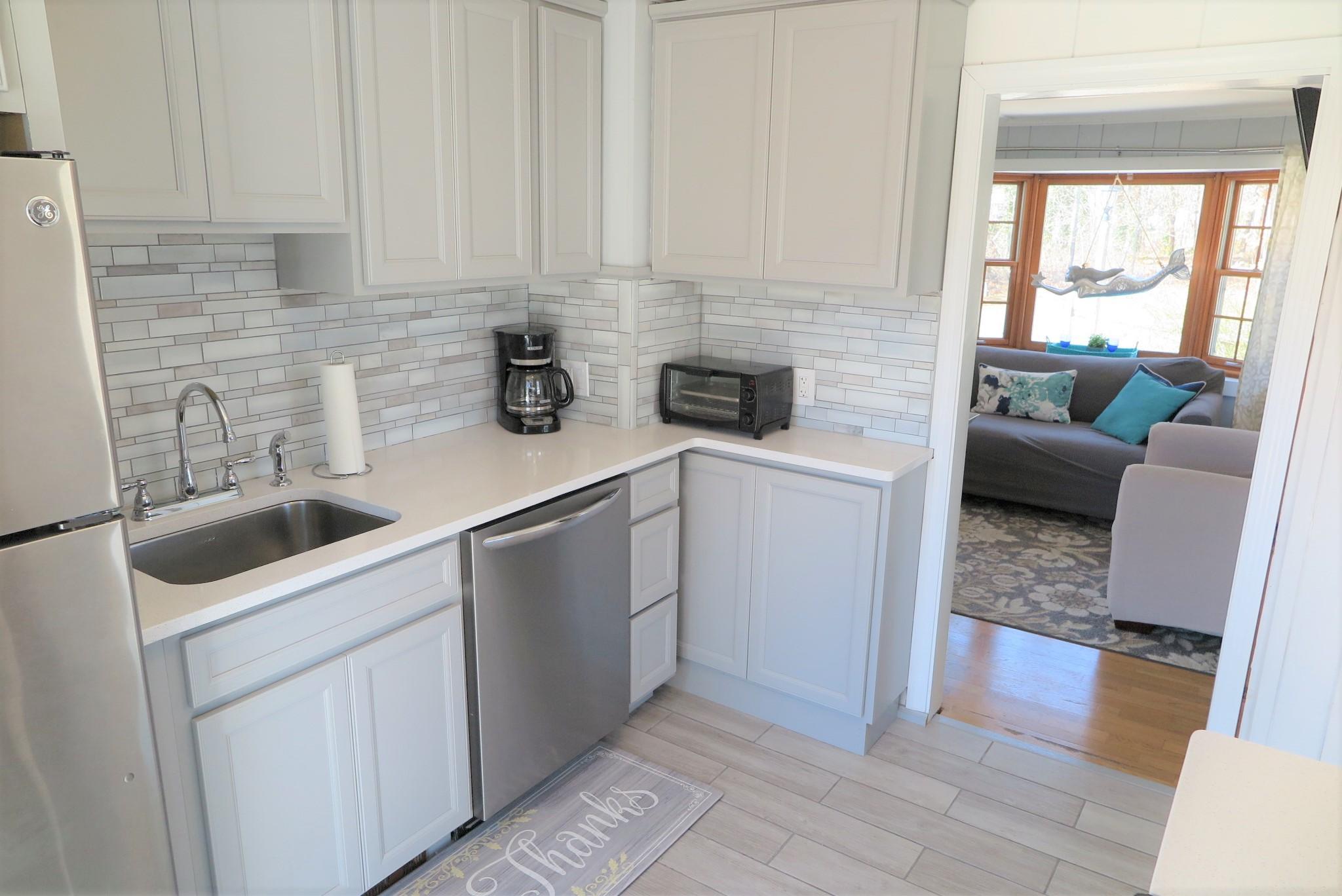 42 Bain Road Dennis Port, MA 02639 - Photo 15 of 46 a kitchen with white cabinets and a wooden floor