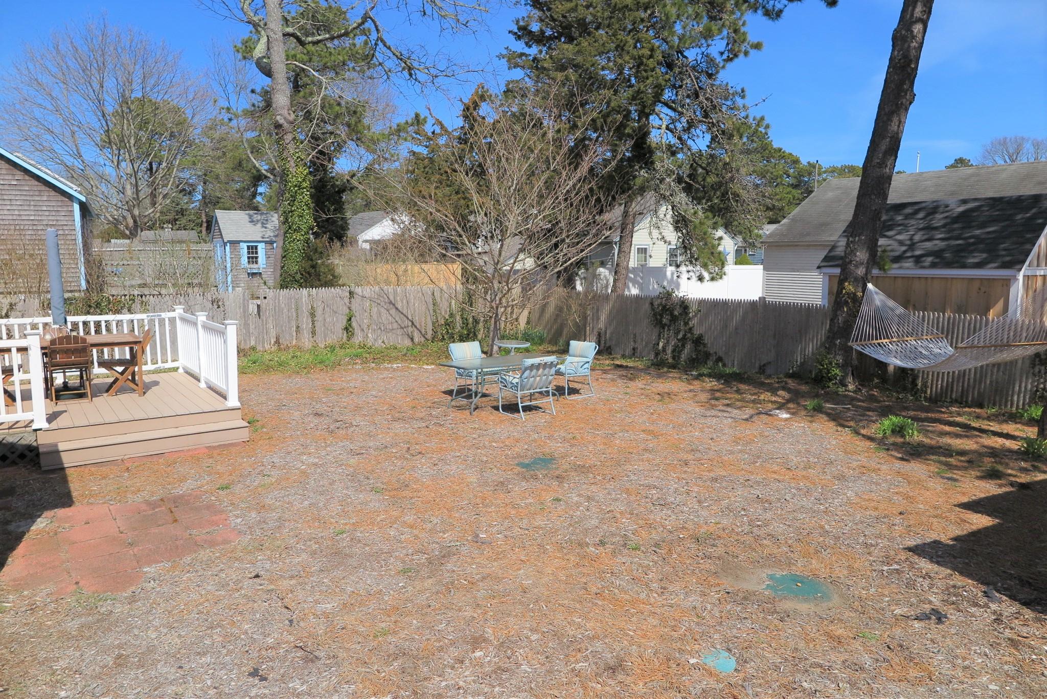 42 Bain Road Dennis Port, MA 02639 - Photo 42 of 46 a view of backyard with a table and chairs and a fire pit