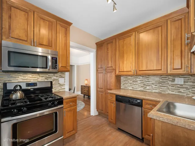 a kitchen with granite countertop wooden cabinets stainless steel appliances and a window