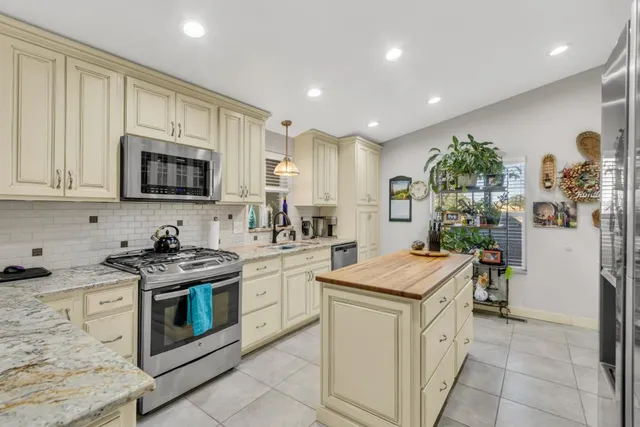 a kitchen with stainless steel appliances granite countertop a refrigerator a stove and a sink