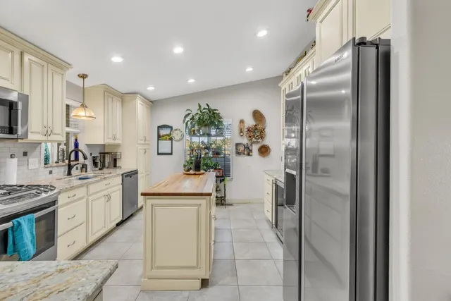 a kitchen with granite countertop a stove a sink and a white cabinets