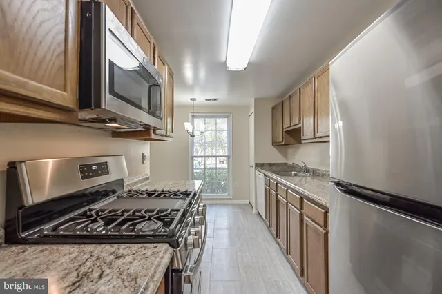 a kitchen with stainless steel appliances granite countertop a stove a sink dishwasher and a microwave oven with white cabinets