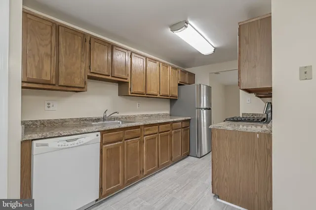 a kitchen with stainless steel appliances granite countertop wooden cabinets a stove top oven a sink and dishwasher