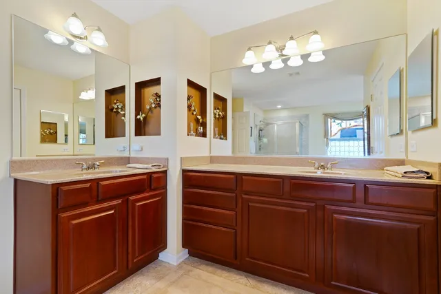 a spacious bathroom with a granite countertop double vanity sink a mirror a window and a bathtub
