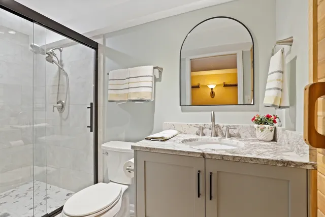 a bathroom with a granite countertop sink toilet and shower