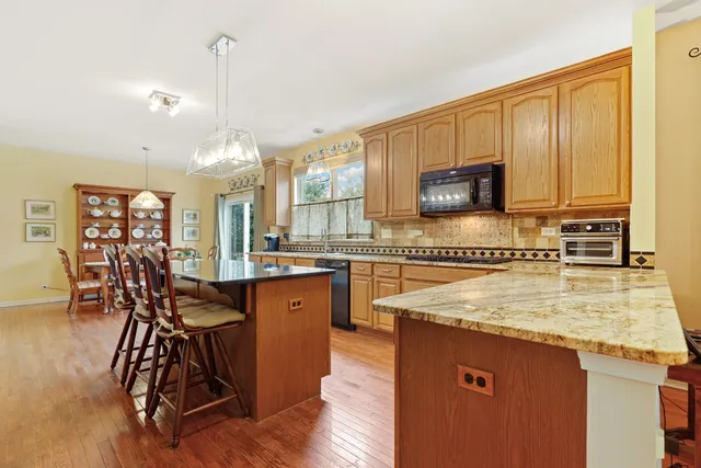 a kitchen with stainless steel appliances granite countertop a table chairs sink and cabinets