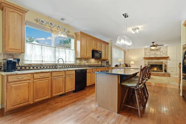 a kitchen with stainless steel appliances granite countertop wooden floor a dining table and chairs