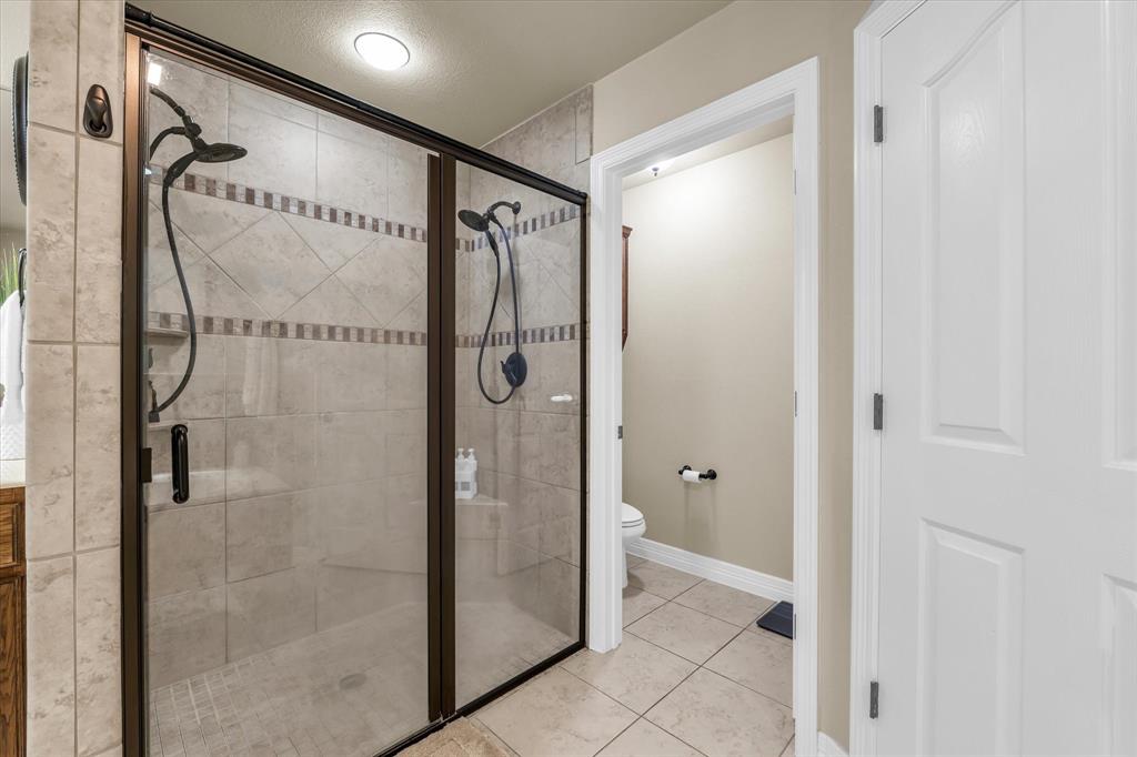 910 Springdale Lane Lorena, TX 76655 - Photo 16 of 39 Tiled shower with a clear glass enclosure and bronze-finish framing